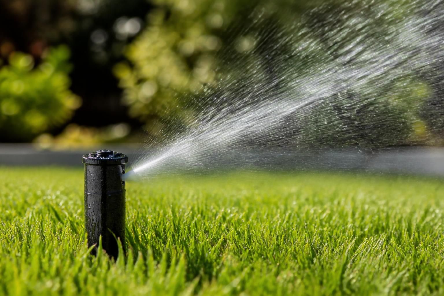 Sprinkler system watering a healthy lawn evenly.